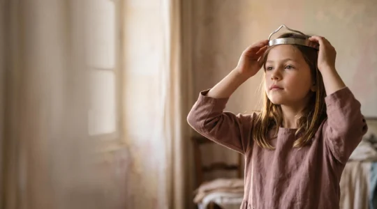 Petite fille se couronnant elle-même avec confiance, symbole d'un jeu de princesse actif plutôt que passif