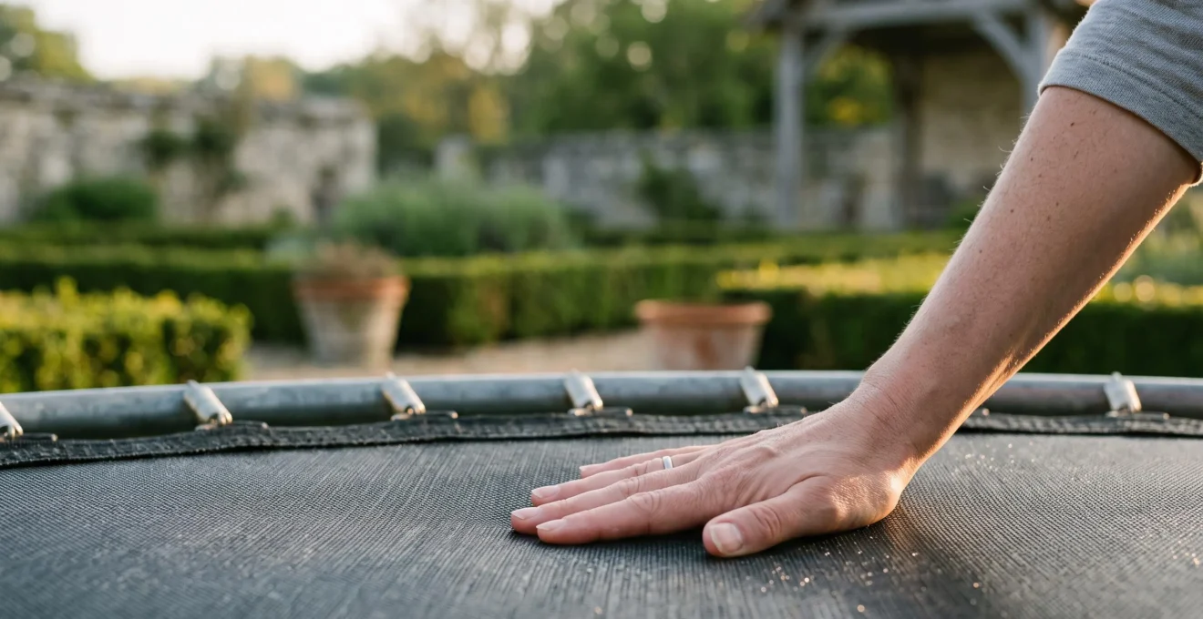 Gros plan artistique sur une toile de trampoline tendue dans un jardin français, symbolisant le test de solidité avant le premier saut
